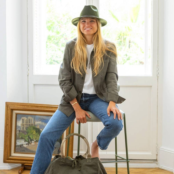 Moss green wool felt fedora hat with leather trim, worn casually with a white t-shirt and olive jacket.