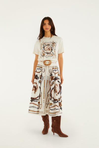 Winter white midi skirt featuring an off-white equestrian print, A-line cut, and removable scarf-style belt. Worn with brown tall boots.