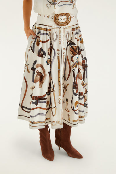 Midi skirt in off-white with equestrian print, featuring an A-line cut and removable scarf-style belt. Worn with tall brown boots.