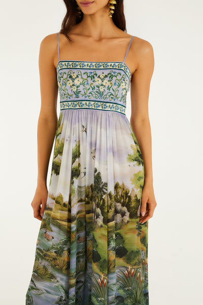Multicolor landscape print maxi dress with a square neckline and adjustable straps, featuring floral detailing and a flowing silhouette.
