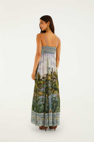 Flowing green multi-print maxi dress with adjustable thin straps, featuring a floral border and landscape details.