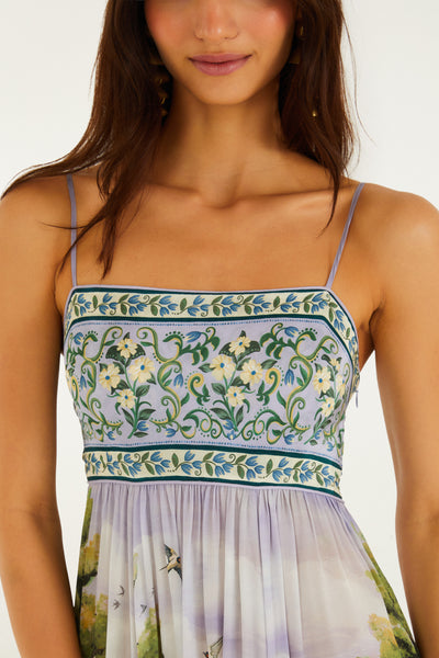 Strappy, square-neck maxi dress featuring a multicolored landscape print with floral borders and flowing viscose fabric.