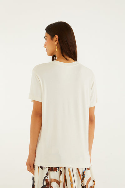 Off-white slim fit t-shirt featuring a round neckline and short sleeves, worn with a patterned skirt.