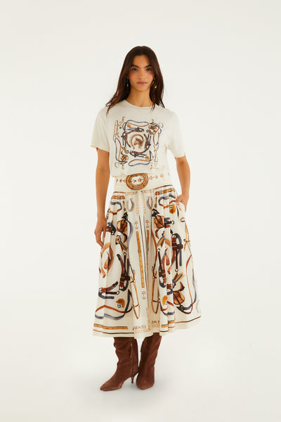 Off-white short sleeve t-shirt with equestrian print in warm terracotta, navy, and gold tones, worn with a patterned skirt.