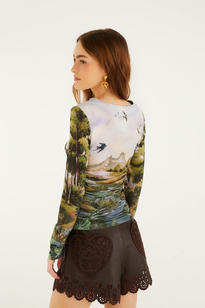 Green multi-print ruched top featuring a countryside landscape design, long sleeves, and a flattering fit.
