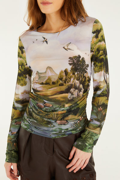 Long-sleeve ruched top featuring a serene countryside landscape print in muted greens and pastels, crafted from soft jersey fabric.