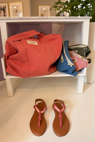 Closet with a pink cotton shopping tote, denim and canvas fanny packs, and brown sandals with pink rope details on a white shelf | Craie Studio | idPearl Boutique New  York