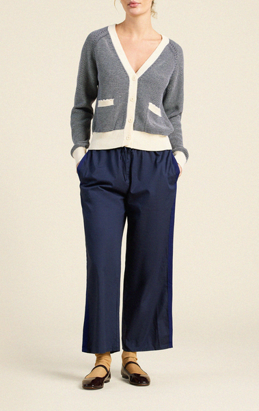 Navy and ivory cotton cardigan with deep v-neck, button front, and two functional pockets, styled over navy trousers.
