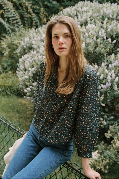 Navy floral blouse made from cotton, featuring a v-neckline and long sleeves, paired with classic blue jeans.