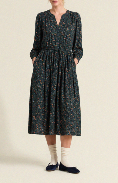 Navy floral midi dress with a V-neckline, 3/4 sleeves, drawstring waist, and hidden pockets, worn with classic flats.