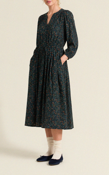 Navy floral midi dress with v-neckline, 3/4 sleeves, and drawstring waist, featuring side pockets. Model wears navy flats.