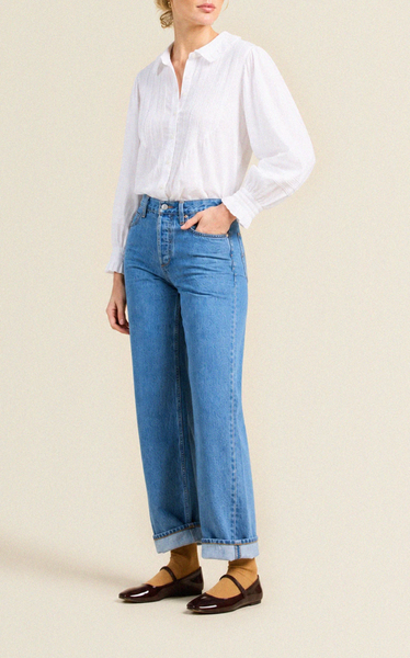 Fitted white cotton voile blouse with oversized collar and pintucked front, worn with blue denim wide-leg jeans.